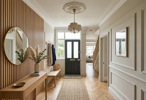 Slat panels in the hallway interior with stucco decor, a round mirror, and a wooden console
