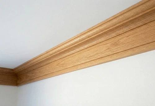 Wide Ceiling Wooden Cornice with a Smooth Profile at the Junction of the Wall and White Ceiling
