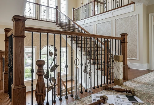 Classic staircase with wooden posts and wrought iron balusters in a bright hallway