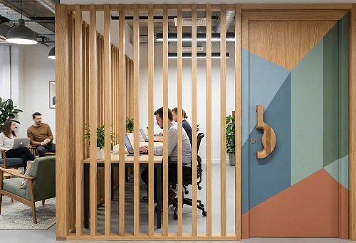 Slatted partition in coworking space made of natural wood &mdash; functional zoning of work areas while preserving light and visual openness