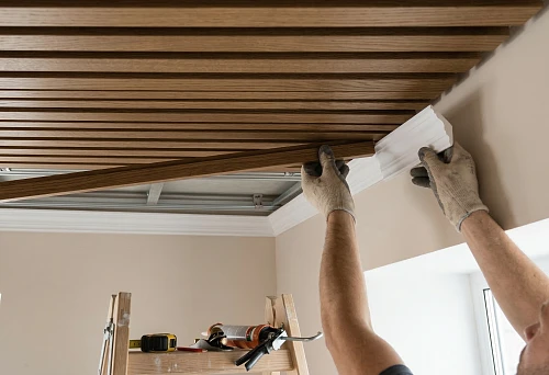 Installation of the final slat ceiling panel with precise fitting at the edge of the ceiling structure