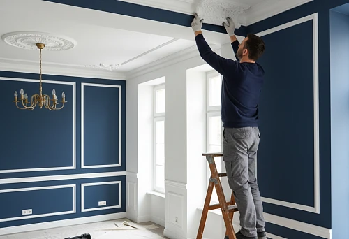 a craftsman installs a polyurethane corner element on a ceiling transition