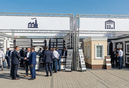 Exhibition stand with samples of polyurethane facade stucco and architectural decor: showcases with cornices, architraves, and columns on demonstration facades.