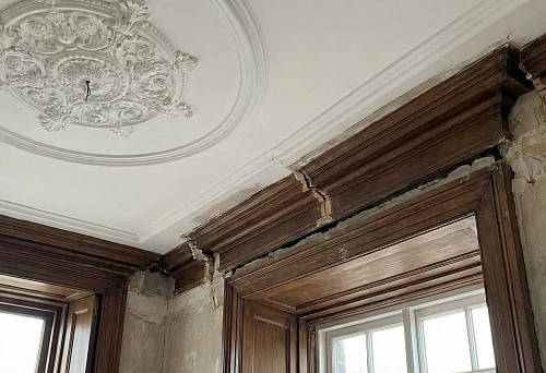 Ceiling molding with decorative rosette and wooden cornice at the wall-ceiling junction, demonstration of installation errors and misalignment of elements