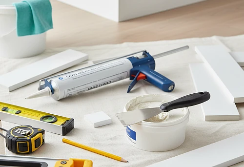 Tools and materials for installing polystyrene skirting boards: glue, putty, level, spatula, and other accessories on the floor before installation