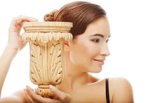 Carved wooden vase held by a woman, symbolizing harmony between nature and art.