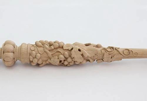 Carved baluster from light wood with a three-dimensional floral pattern and grape clusters