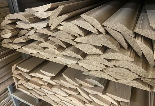 Wooden planks and battens for wall finishing, neatly arranged on metal shelves in a warehouse
