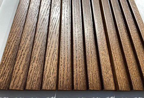 Close-up of a wooden baseboard plank in warm tone with pronounced natural wood grain texture.