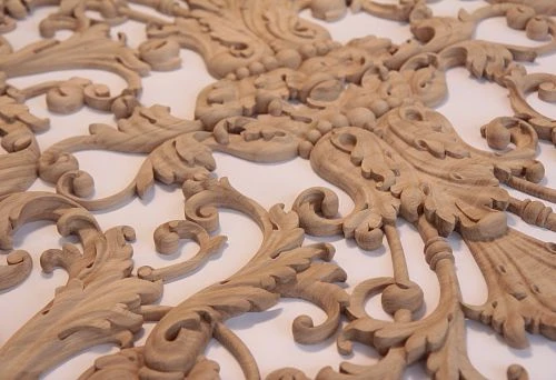 Detailed carved wooden elements with elegant scrolls and botanical motifs, arranged on a light background.