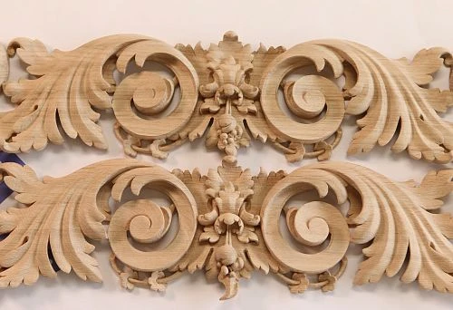 Paired carved decorative elements made of solid wood, shaped as stylized leaves and scrolls.