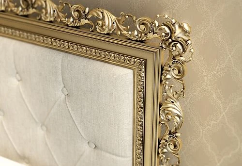 Luxurious wooden bed with carved golden decor on the headboard, styled in classic design against elegant wallpaper.