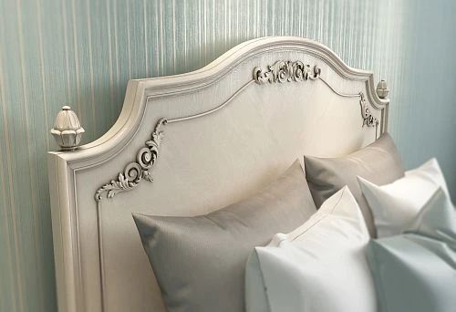 Elegant light-colored bed headboard with delicate carving and soft decorative elements in classic style against background