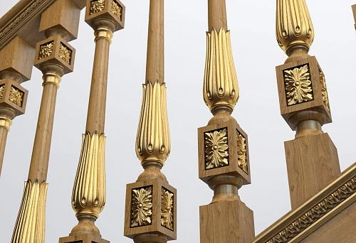 Turned balusters with gold finish and carved decoration on a wooden staircase