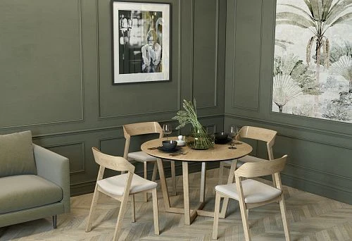 Interior with round wooden table and solid wood chairs with soft seats in Scandinavian style