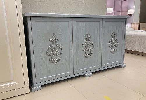 Light-colored dresser with classic carving and decorative elements in the bedroom interior