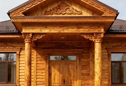 House with wooden facade decor featuring carved columns and pediment
