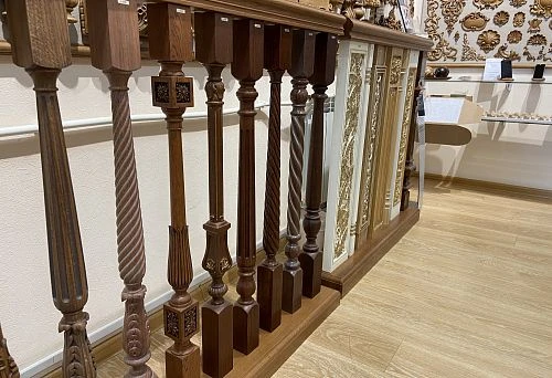 Photos of wooden balustrades and columns with various carved elements and decorative panels, located in an exhibition hall with wooden floors and walls adorned with ornaments.