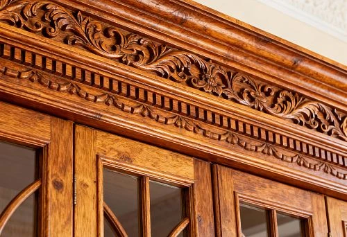 Carved wooden molding with ornament in Russian style above natural wood cabinet doors