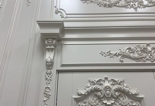 Snow-white decorative door frame surround with stucco decoration and elegant architectural forms in classic interior style