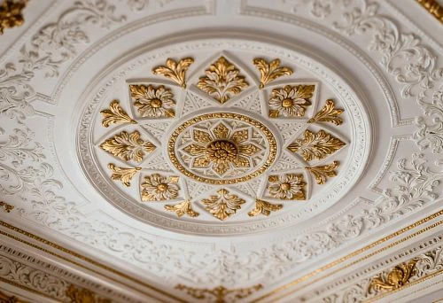 Ceiling rosette and moldings with gold elements in a classic interior.