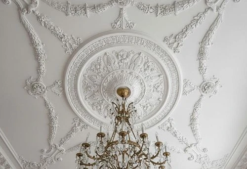 Snow-white ceiling medallion for chandelier with a round rosette and decorative ornaments in classic style