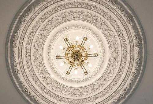 Ceiling rosette with stucco decoration and symmetrical patterns around the chandelier in a classic interior