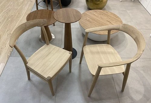 Two unpainted wooden chairs with curved backrest and minimalist design