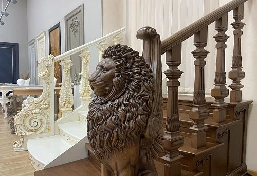 Oak staircase with carved balusters and large lion sculpture at the base