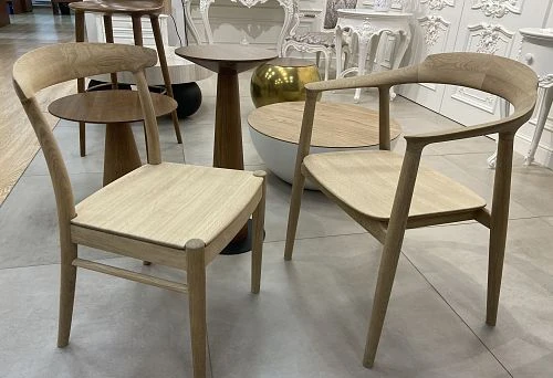 Two designer chairs made of solid oak with curved backrest and minimalist silhouette