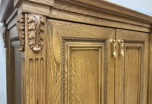 Oak cabinet with carved leaf motifs and golden hardware