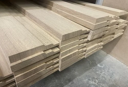 Various-width wooden skirting boards on a metal shelf in the warehouse