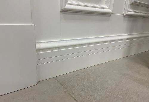 Heavy white baseboard in a classic interior combined with decorative elements and tiled flooring