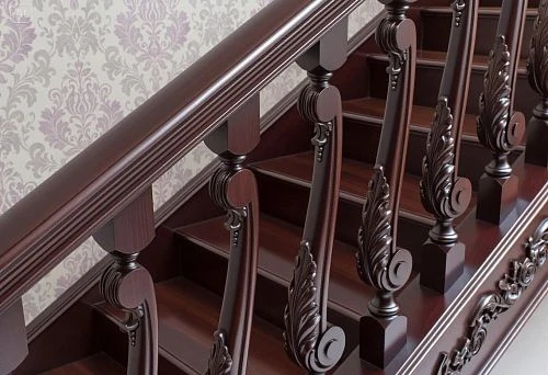 Staircase with professionally installed carved balusters and handrails made of dark wood against classic wallpaper