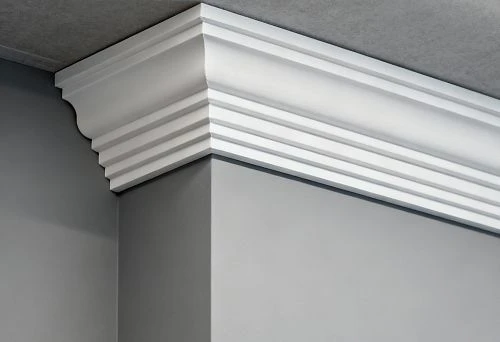 White ceiling profile installed on an internal wall corner, demonstrating the shape and relief of polystyrene or polyurethane skirting board