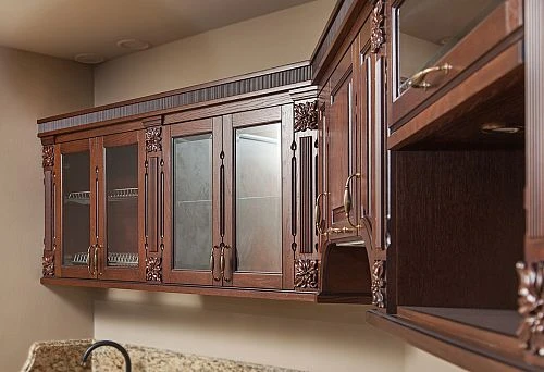 Classic kitchen set made of dark solid wood with decorative carving and glass fronts