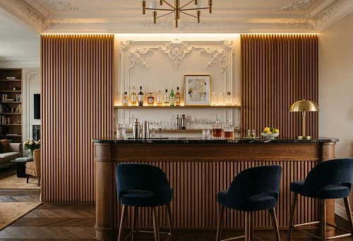 How to design a home bar with wooden slats, stucco decor, moldings, and trim. Ideas for the wall behind the bar counter, wine area, shelves, and lighting.