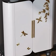 White chest of drawers in the interior, decorated with polyurethane molding in the form of butterflies and botanical patterns.